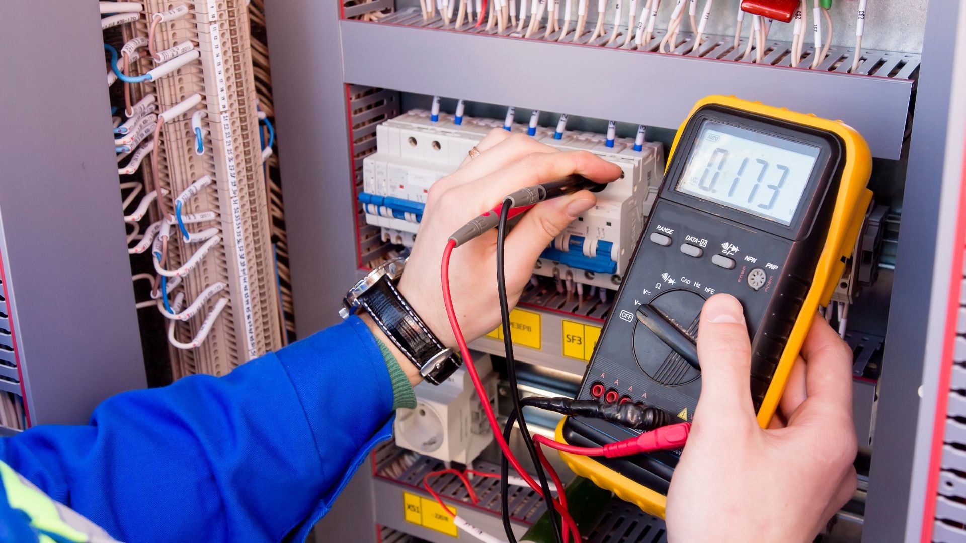 Electrician using multimeter to test voltage in electrical circuit panel